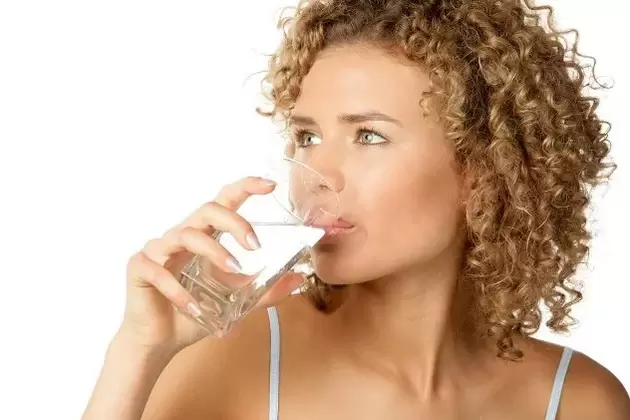 A lány diétát követ a lusták számára, evés előtt iszik egy pohár vizet